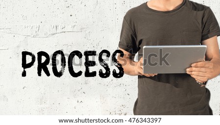 Young man using tablet pc and PROCESS concept on wall background