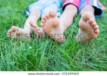 Group of happy children feet lying on green grass outdoors in summer park
