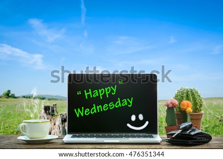 Laptop on wooden table, Happy Wednesday text on screen .
