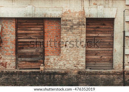 Old vintage sealed windows on the worn peeled yellow brick wall. Abandoned factory warehouse. Industrial texture background. Soviet architecture.
