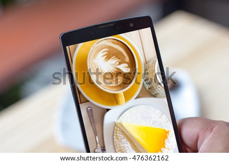 A man show nice coffee and cake Photo on his smartphone that he took before eating ,Lifestyle take photo before eating