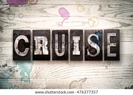 The word "CRUISE" written in vintage, dirty metal letterpress type on a whitewashed wooden background with ink and paint stains.