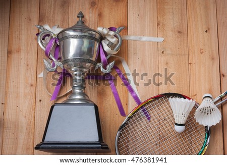 Shuttlecocks, rackets and  badminton trophy on wood background