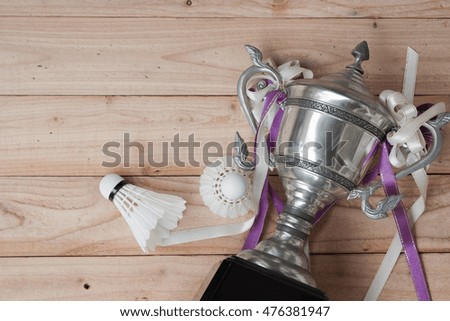 Shuttlecocks and  badminton trophy on wood background