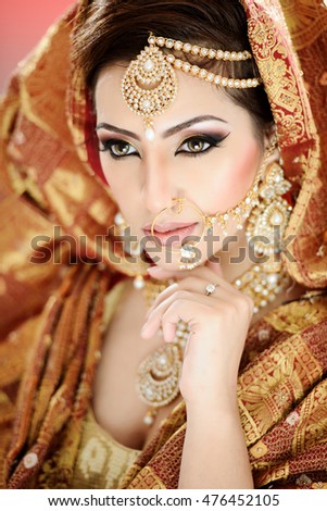 Portrait of a pretty girl in traditional Indian Pakistani bridalwear with heavy jewelry and makeup