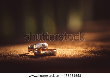 Blurred picture of sparkling wedding rings lying on the brown cloth