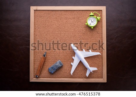 travel concept with corkboard smartphone notebook and transport toys with alarmclock and red heart object on black and white background
