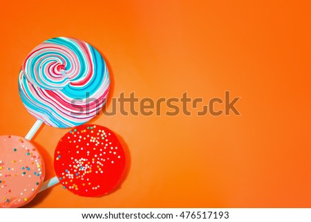 Vintage orange background with three varicolored candy. Space for copy.