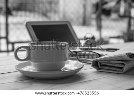 Black and white mug of coffee and a newspaper on the table.