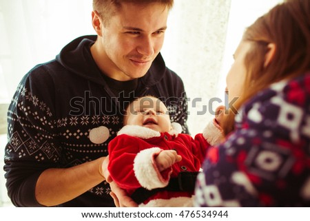 Man in black pyjama holds his little son dressed like Christmas elf