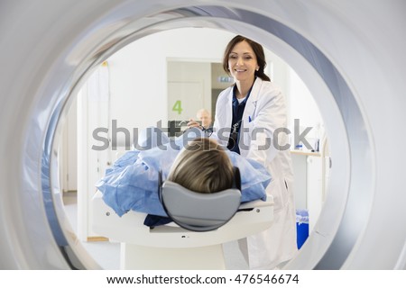 Female Doctor Looking At Patient Undergoing CT Scan Royalty-Free Stock Photo #476546674