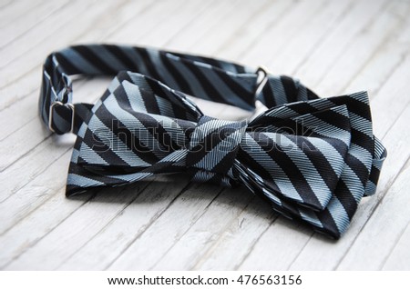 Striped blue bowtie on a wooden background. Accessory for formal dress. Symbol of elegance and fashion for men. Men's casual. Men's and women's accessories. Men's and women's bow tie. Royalty-Free Stock Photo #476563156