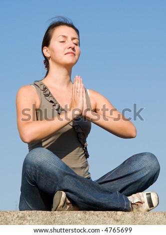 Meditation. The girl meditates with sky at background.