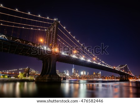 Manhattan Skyline and Manhattan Bridge At Night. Manhattan Bridge is a suspension bridge that crosses the East River in New York City