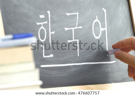 Hand writing on a blackboard in a Korean class with the word "Korean" wrote in. Some books and school materials. Royalty-Free Stock Photo #476607757