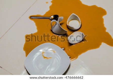 Coffee spilled with cup broken on white floor 
