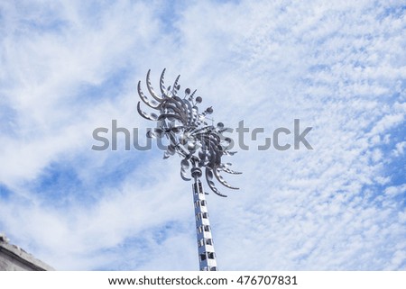 Weather wind vane against cloudy sky