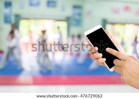 woman use mobile phone and blurred image of people in taekwondo class