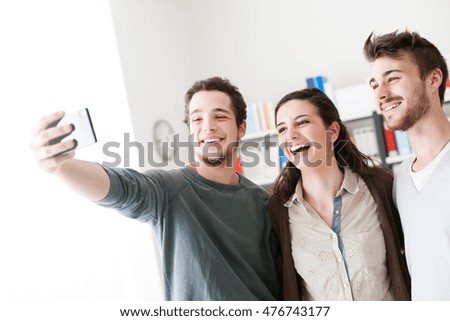 Smiling happy teenagers taking selfies with a mobile phone, sharing, technology and friendship concept