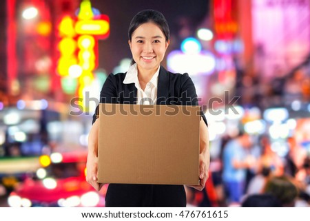 A young woman carrying a box on night market background