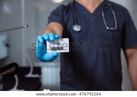 Male doctor showing visiting card and looking at camera
