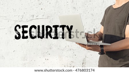 Young man using laptop and SECURITY concept on wall background