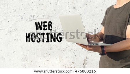 Young man using laptop and WEB HOSTING concept on wall background
