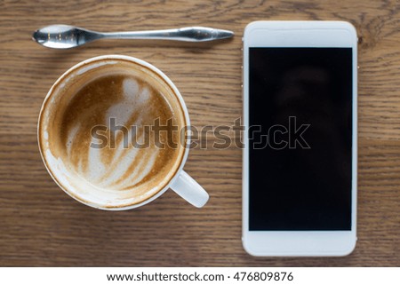 Coffee cup and smartphone on wooden table. View from above