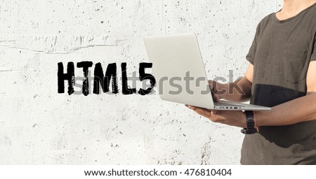 Young man using laptop and HTML5 concept on wall background