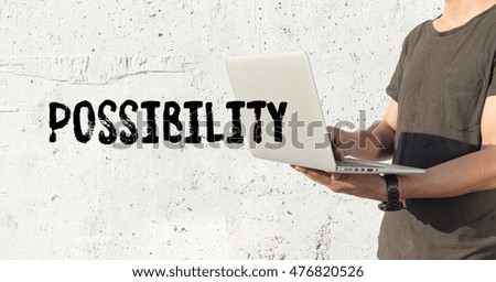 Young man using laptop and POSSIBILITY concept on wall background