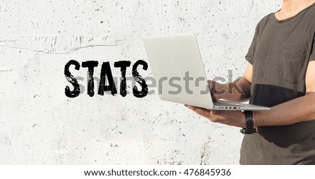 Young man using laptop and STATS concept on wall background