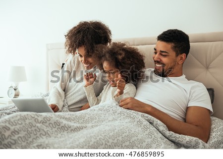 African american family looking at a laptop in a bed.