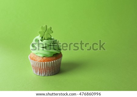 Tasty cupcake with clover on green background. Saint Patrics Day concept
