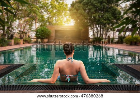 Vacation lifestyle scene of young woman sitting in swimming pool in morning time. Weekend and holiday lifestyle concept Royalty-Free Stock Photo #476880268