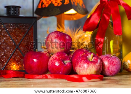 Red apples, orange lantern, a bottle of sunflower oil, ears of wheat and rye - cozy picture with orange for Thanksgiving and Halloween. Autumn Gifts.