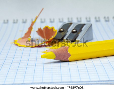 sharpened yellow pencil with shavings and sharpener in background, shallow depth of field