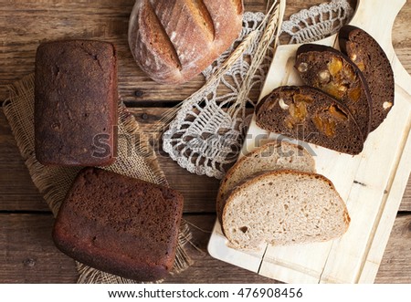 Homemade rustic wheat bread, rye bread and bread with dried apricots, figs and hazelnuts on a wooden table. Selective focus.