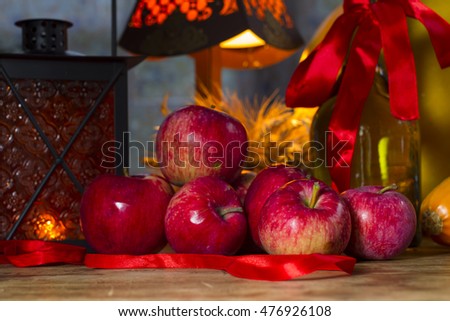 Red apples, orange lantern, a bottle of sunflower oil, ears of wheat and rye - cozy picture with orange for Thanksgiving and Halloween. Autumn Gifts.