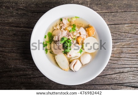 Noodles of Thai style clear soup in traditional ceramic bowl on old wooden table. view from above Royalty-Free Stock Photo #476982442