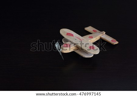 
toy airplane from rough tree on a dark background. Propeller made of tin.