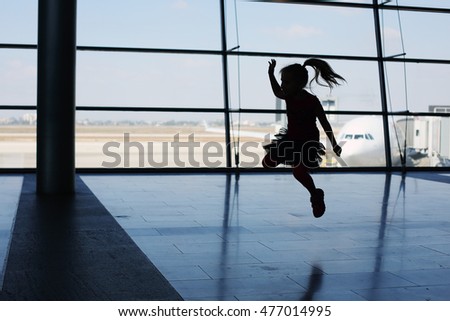 Silhouette of cute girl jumping in front of the window in airport