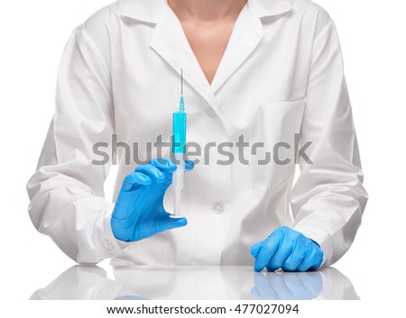 Close up of female doctor in white medical gown and blue sterilized surgical gloves holding plastic medical syringe filled with blue drug against white background