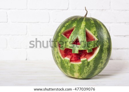 Smiling face of a watermelon on a Halloween like a pumpkin for Halloween. Copy space for text