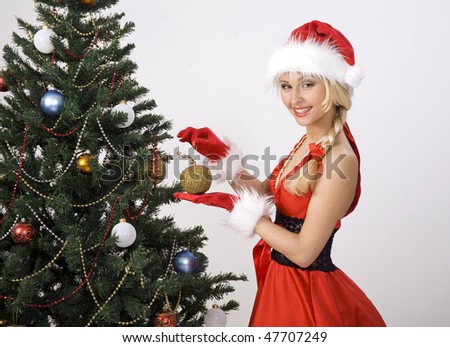 The girl in a suit of Santa at a Christmas fur-tree.