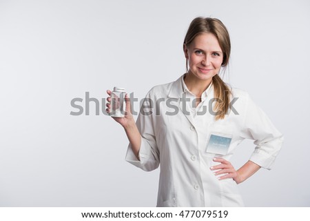 Young smiling female doctor presenting a white unlabeled bottle or recipient of pills