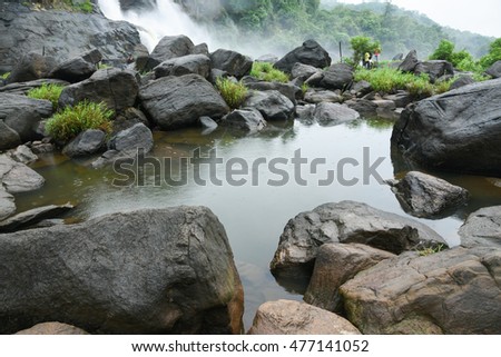 River filled with rocks at Athirapally Vazhachal waterfall in Kerala South India. holiday location Monsoon Indian Water fall . Relaxing enjoying freedom/watching rain, green misty forest