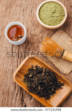 green tea powder and dried tea leaves on wooden background