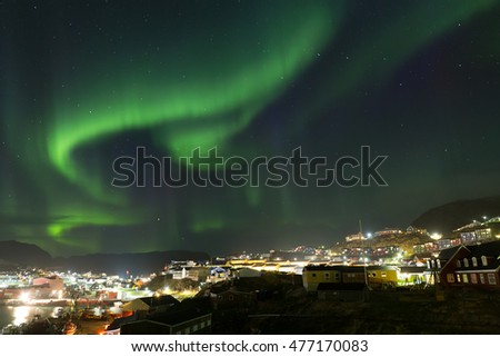 Northern lights in the sky above colorful house city in qaqortoq greenland.