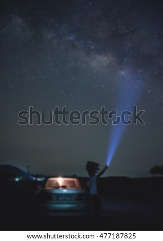 Blurred photo of a man pointing light at milky way in night time 