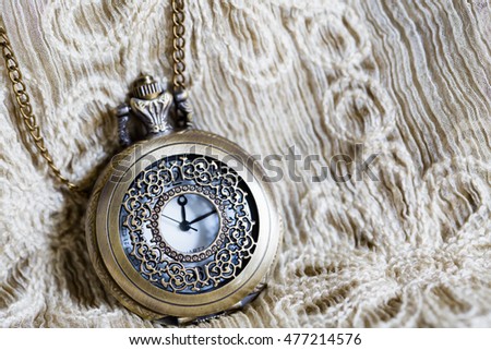Beautiful vintage pocket watch on elegrant beige fabric background after midnight concept